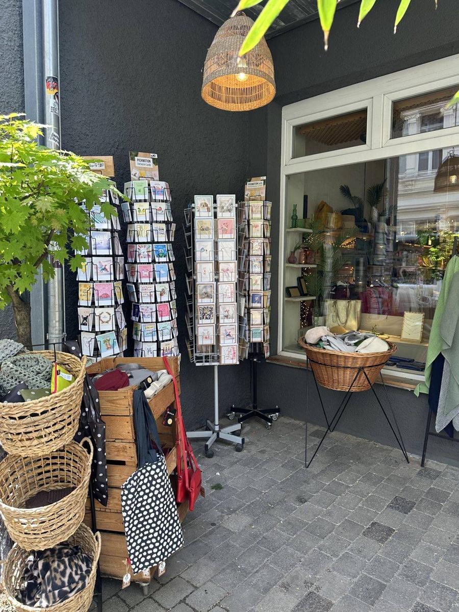 Postkartenständer und Körbe neben dem Schaufenster